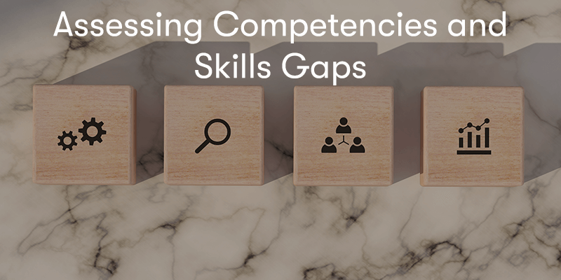 4 woods block with competencies on each with the text Assessing Competencies and Skills Gaps above them with a marble background