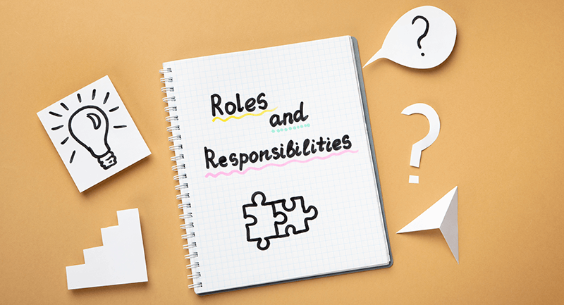 Roles and Responsibilities written on a notepad with an orange background