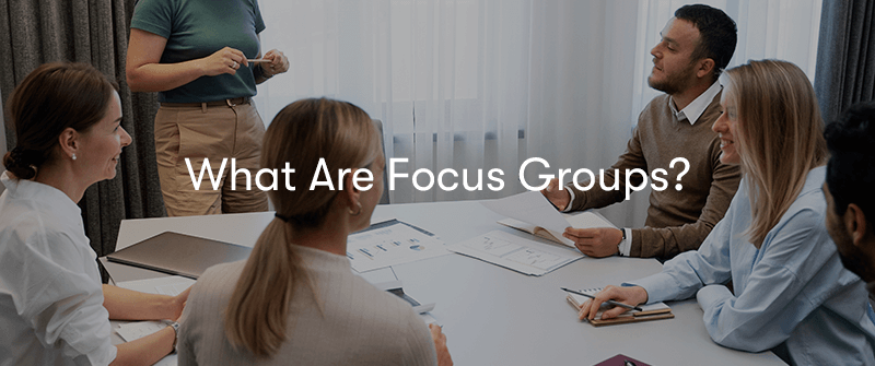 a group of people sat around a table with sheets of data on the table having a discussion. With what are focus groups? text in front.