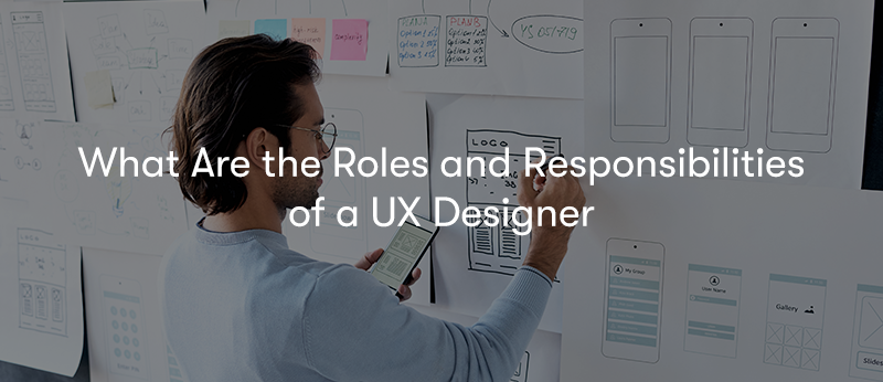 A man stood in front of a wall full of pieces of paper with UX designs on the with the words 'What Are the Roles and Responsibilities of a UX Designer' in front
