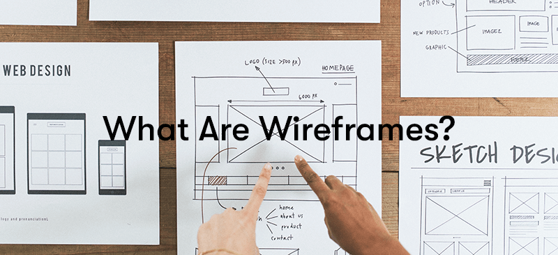 a picture of two hands pointing at pieces of paper with wireframes drawn on them, with the text 'What Are Wireframes?' in front.