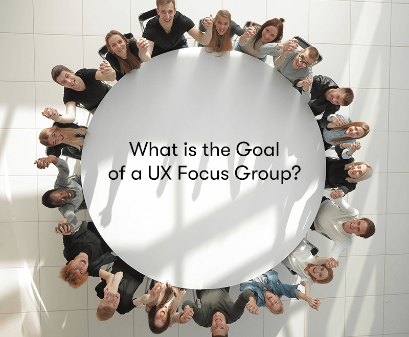 A group of people sat around a round white table all holding hands and putting them in the air, with the words 'What is the Goal of a UX Focus Group' in the middle of the table.