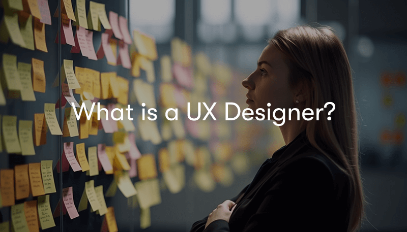 a woman looking at a wall full of post-it notes with writing on, with the words What is a UX designer? on top